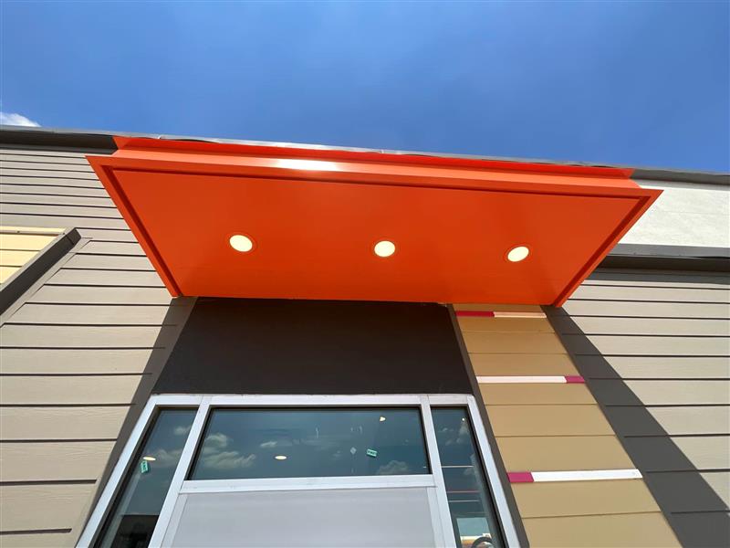 Orange awning with three recessed lights over storefront